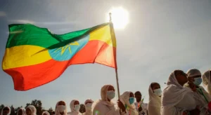 A group of veiled and masked Ethiopian women gathered. One of them is holding up an Ethiopian flag on a small mast