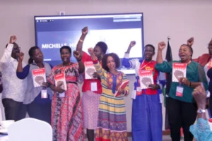 A group of activists from the Great Lakes Region holding up their right hands in solidarity while holding the same copy of a book.