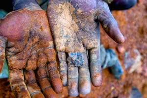 A miner shows out his palms after as session of mining