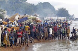 A large group of people by the shores of a river or lake in the Great Lakes Region of Africa.