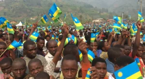 A large gathering of Rwandan citizens holding up Rwandan hand flags during Rwandan Liberation Day