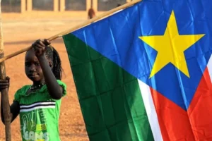 A young Sudanese child hoisting the Sudanese flag