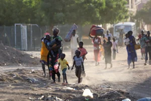 Civilians walk with their belongings as they escape the effects of war in Sudan