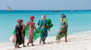 A group of women from Tanzania walk the sandy shores of the ocean