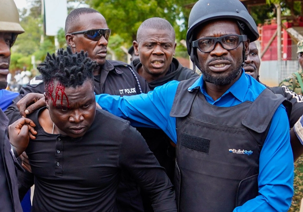 Robert Kyagulanyi aka Bobby Wine walks alongside an injured protester